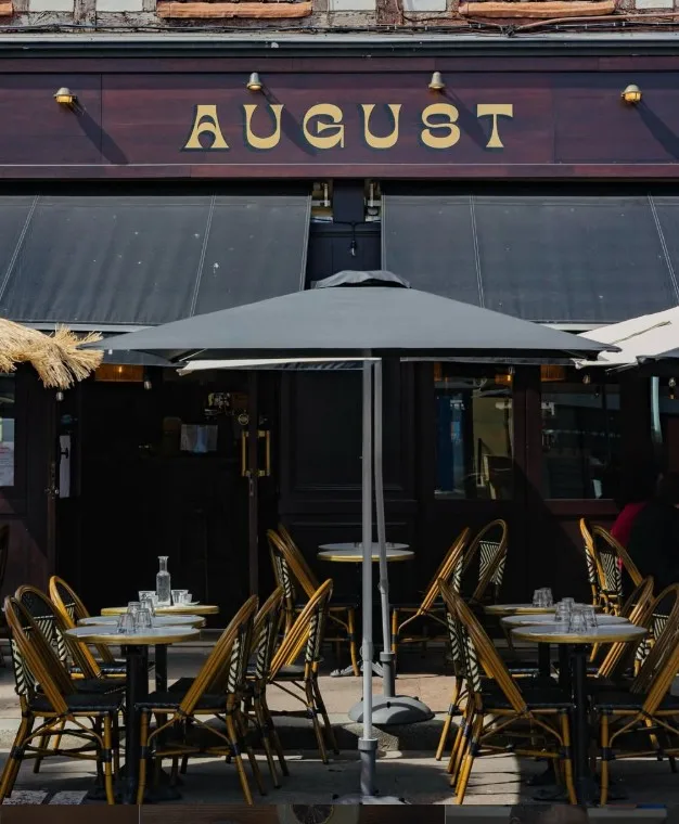 Terrasse d'August place Saint-Marc à Rouen, tables rondes et chaises bistrot sous parasol, par beau temps.
