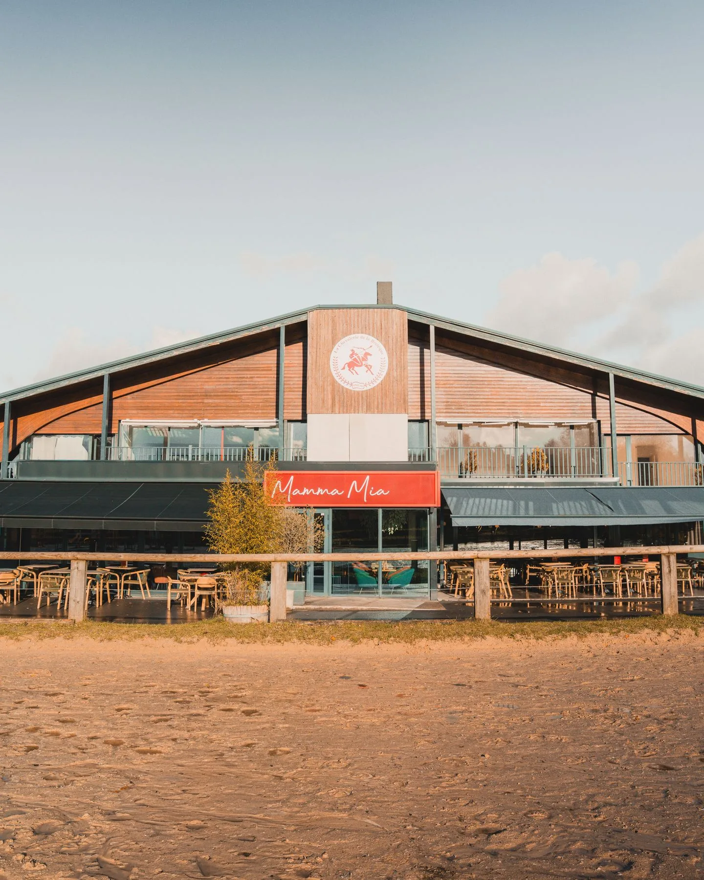 Façade en bois et toit en pente du restaurant Mamma Mia, vu depuis la carrière équestre de la Bretèque à Bois-Guillaume