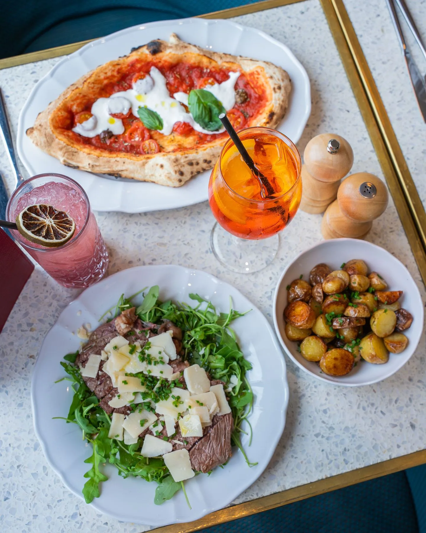 Pizza Margherita à la burrata cuite au feu de bois, carpaccio de bœuf à l'italienne, pommes de terre sautées et spritz servis chez Mamma Mia