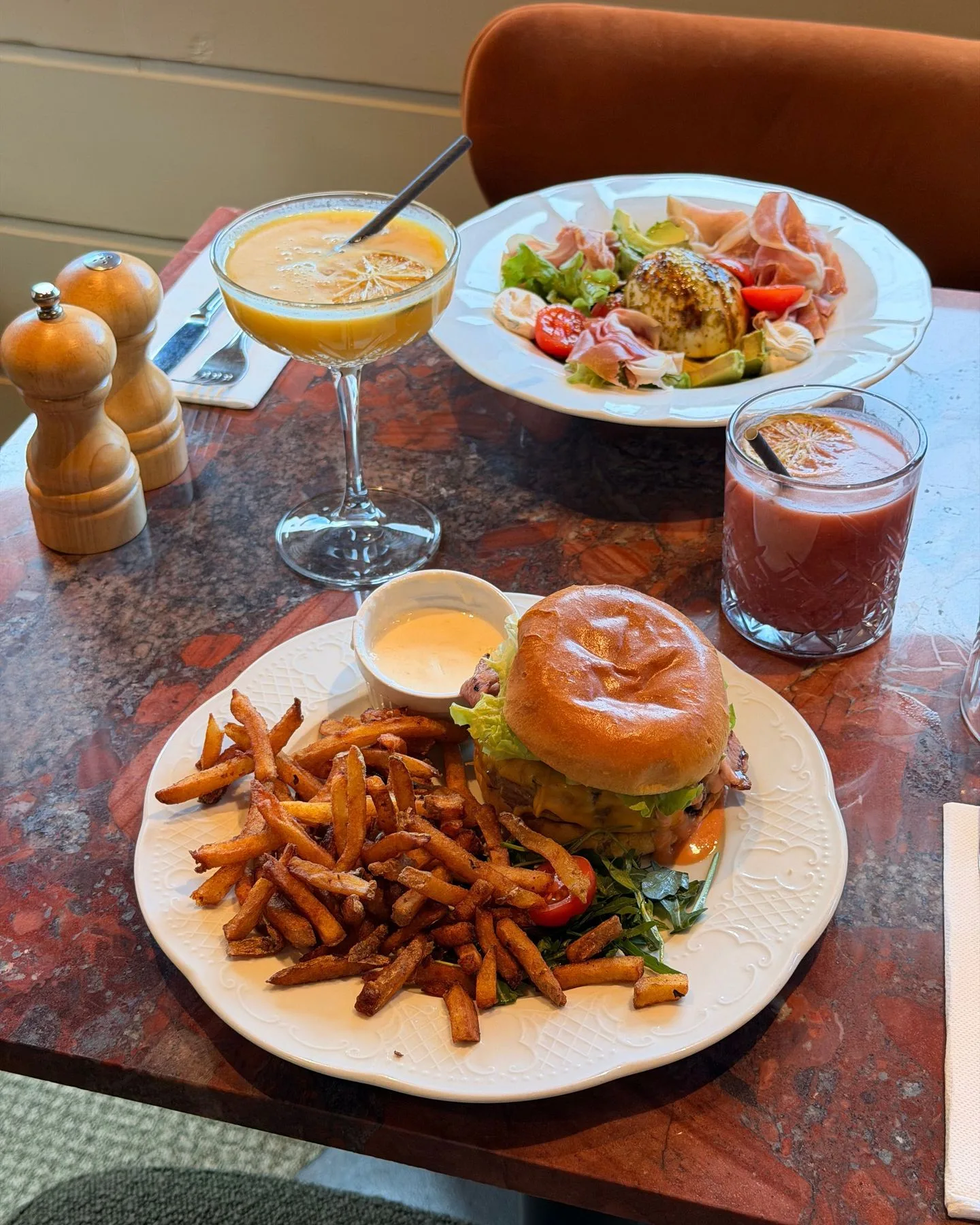 Burger Mimosa servi avec des frites maison généreuses, salade composée au saumon et cocktails en accompagnement